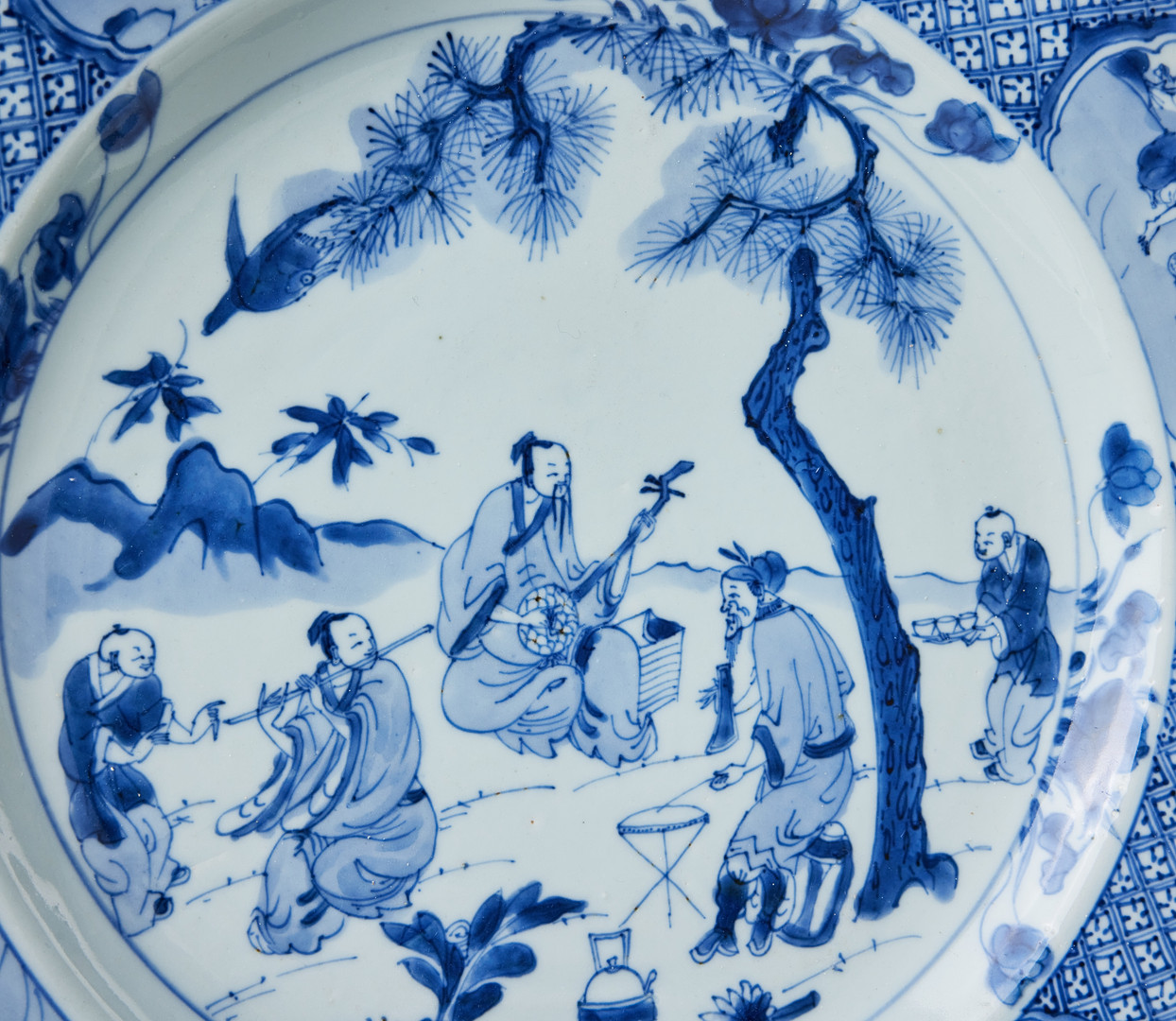 FAT, porslin, Kina, tidig Qianlong (1736-1795), spegeln med dekor av musicerande sällskap under tall i underglasyrblått, brättet med grillage och infällda kartuscher med figurscener.