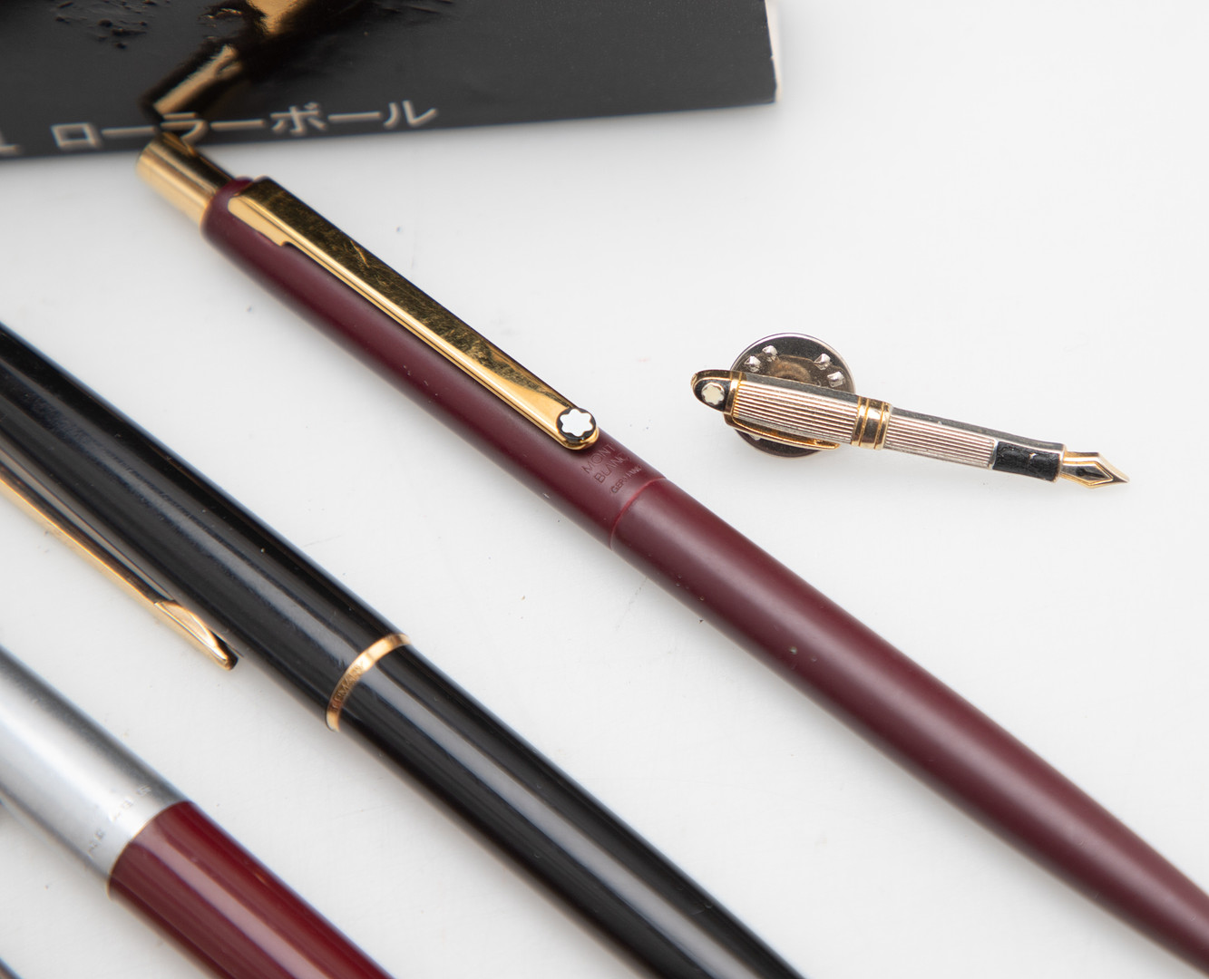 MONTBLANC. Kleine Montblanc-Sammlung: 3 Kugelschreiber, 1 Bleistift, 1 Button und 1 Etui mit Rollerball-Minen, 1 Blechdose und ein Buch (8).