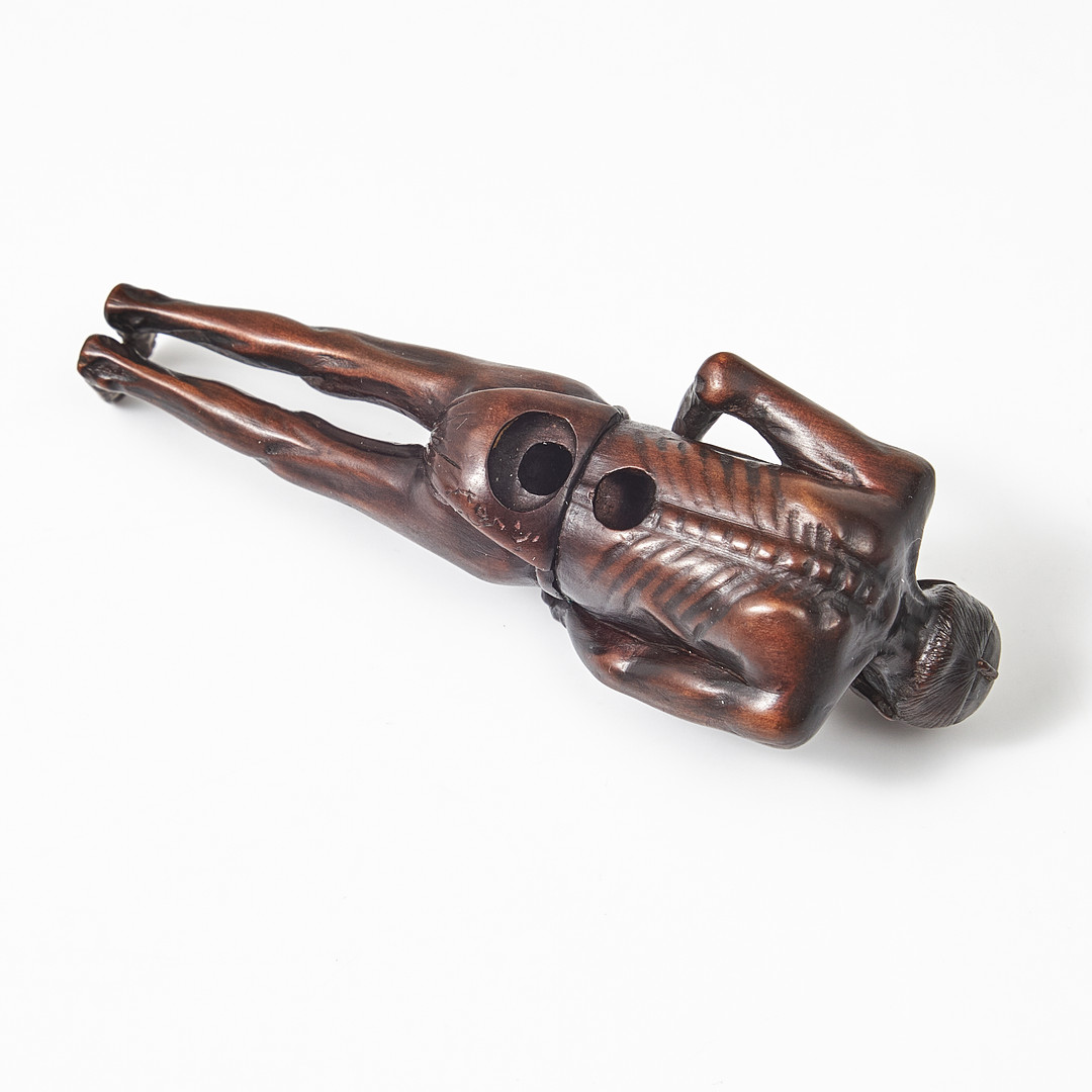 NETSUKE, trä, Japan, 1800-tal, föreställande en man som knyter sitt höftskynke.