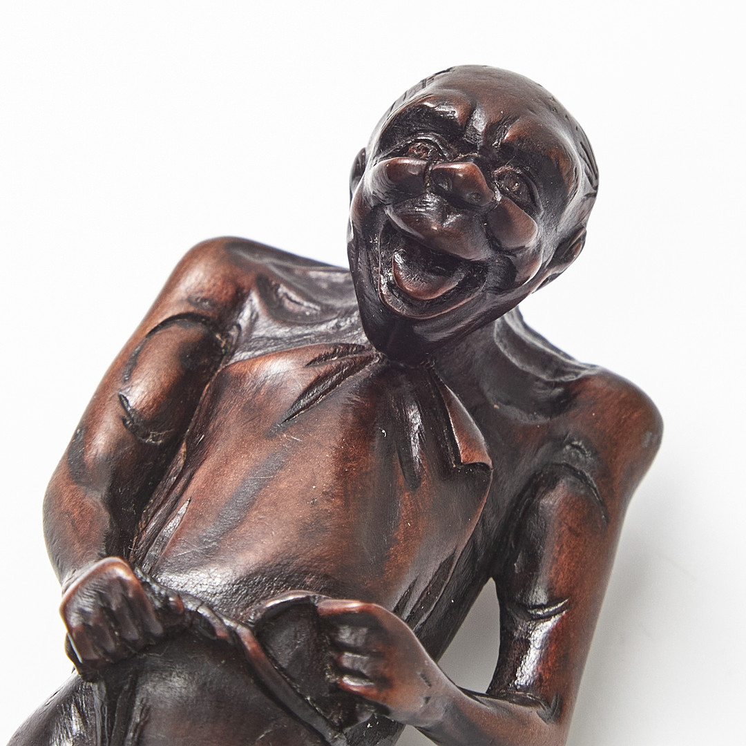 NETSUKE, trä, Japan, 1800-tal, föreställande en man som knyter sitt höftskynke.