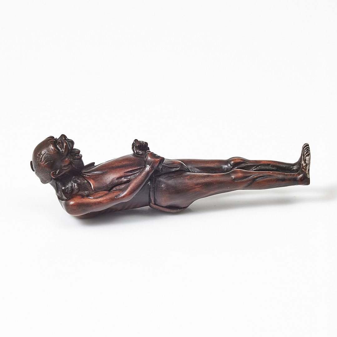 NETSUKE, trä, Japan, 1800-tal, föreställande en man som knyter sitt höftskynke.