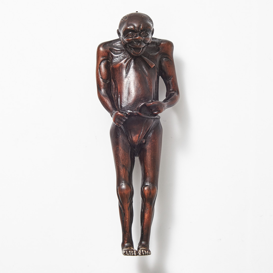 NETSUKE, trä, Japan, 1800-tal, föreställande en man som knyter sitt höftskynke.