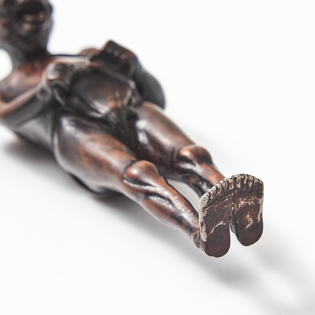NETSUKE, trä, Japan, 1800-tal, föreställande en man som knyter sitt höftskynke.