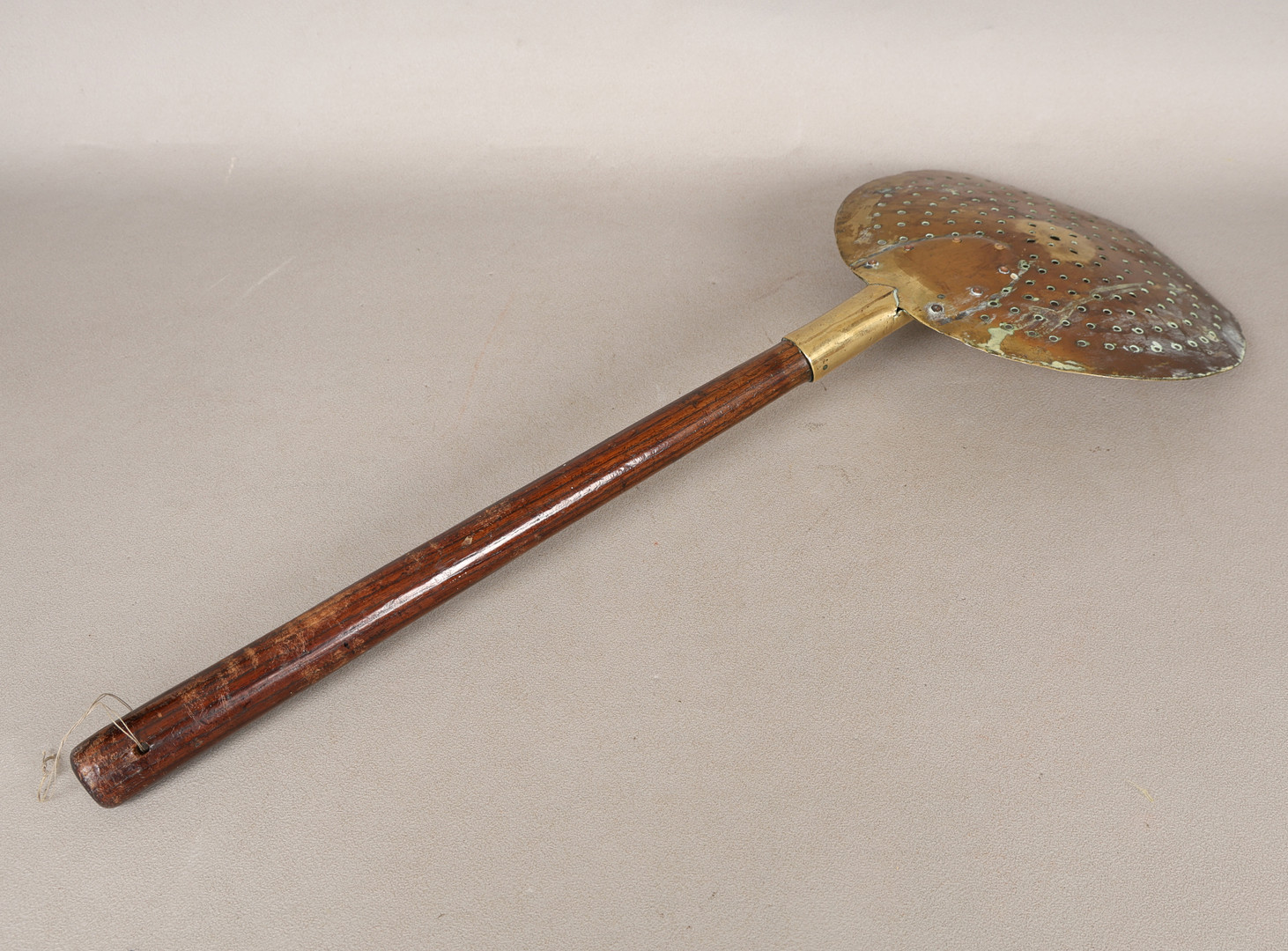 AN 18TH CENTURY BRASS AND OAK HANDLED SKIMMER.