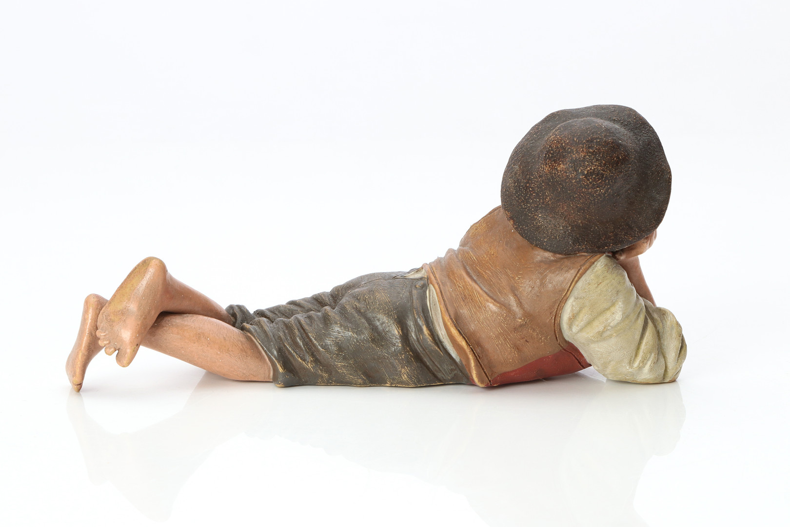 FIGURIN. Bemålad keramik. Vilande pojke. 18/1900-tal. Märkt undertill.
