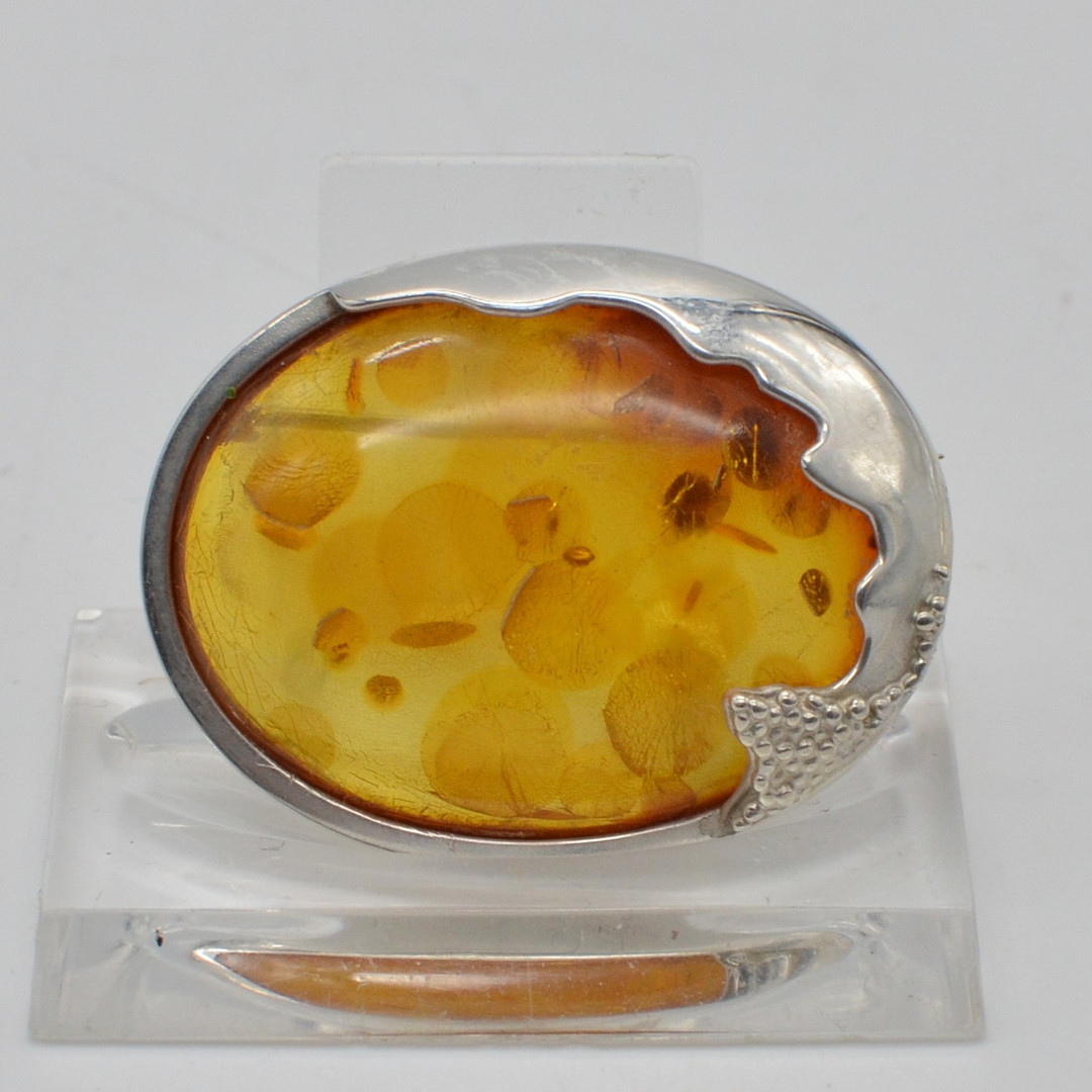 DESIGNERBROSCHE MIT BERNSTEINCABOCHON, BLATTEINSCHLÜSSEN, HANDGEMACHTE FASSUNG AUS STERLINGSILBER, 20. JAHRHUNDERT.