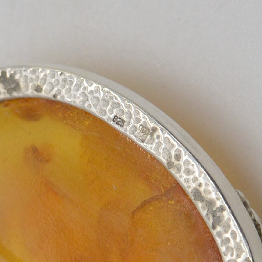 DESIGNERBROSCHE MIT BERNSTEINCABOCHON, BLATTEINSCHLÜSSEN, HANDGEMACHTE FASSUNG AUS STERLINGSILBER, 20. JAHRHUNDERT.