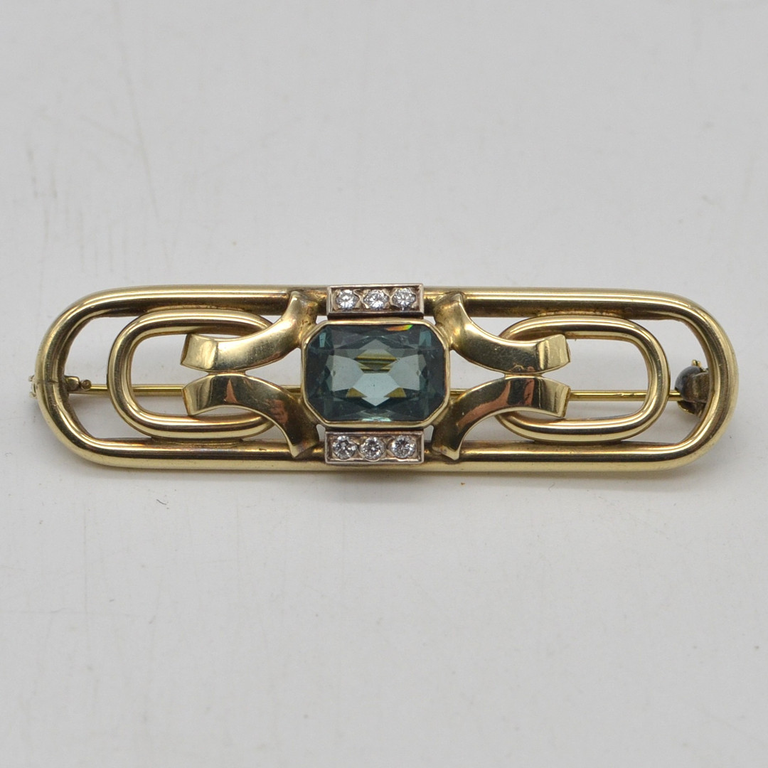 ART DÉCO DESIGNERBROSCHE, BRILLANT UND FACETTIERTER FARBSTEIN, DURCHBROCHENE FASSUNG, FRÜHES 20. JH., "DORESLI" PUNZIERT.