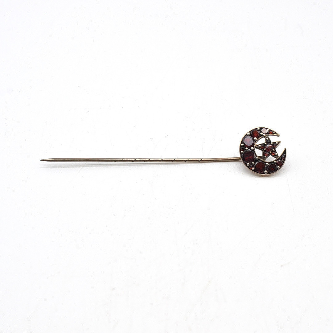 JUGENDSTIL KRAWATTENNADEL MIT GRANATEN, MOND UND STERN, UM 1900.
