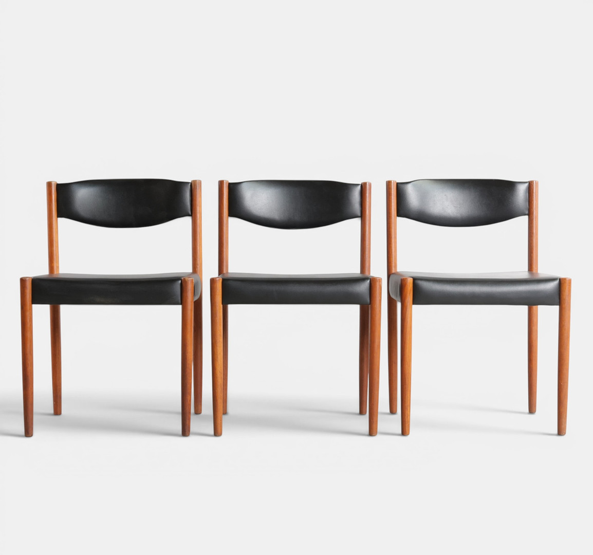 Sæt på tre spisestole med stel af teak, sæde og ryg betrukket med sort skai. Udført og mærket hos Nova Møbler. Danmark, 1960'erne (3).