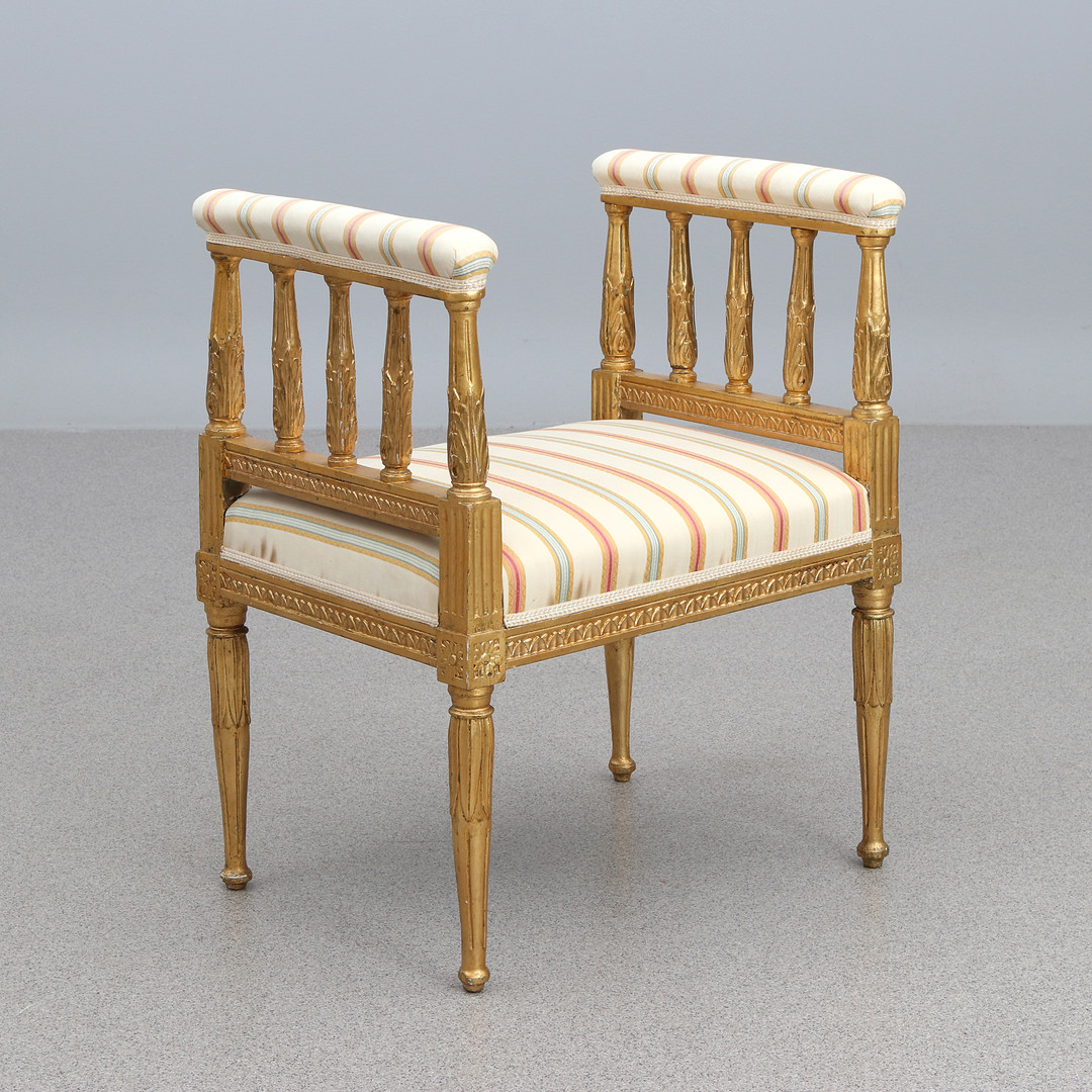 TABURETT. Skuret, skulpterat och bronserat trä med textilklädsel. Gustaviansk stil, 1900-talets första hälft.