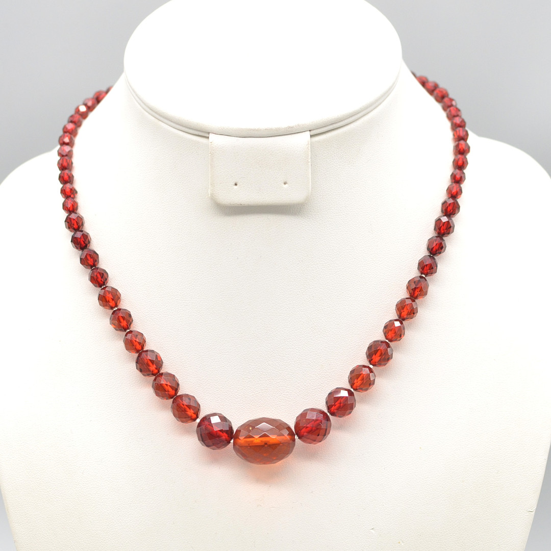 ART DECO BAKELIT PERLENCOLLIER MIT EINEM ROTEN BERNSTEIN, FACETTIERT, SCHRAUBVERSCHLUSS, UM 1930ER.