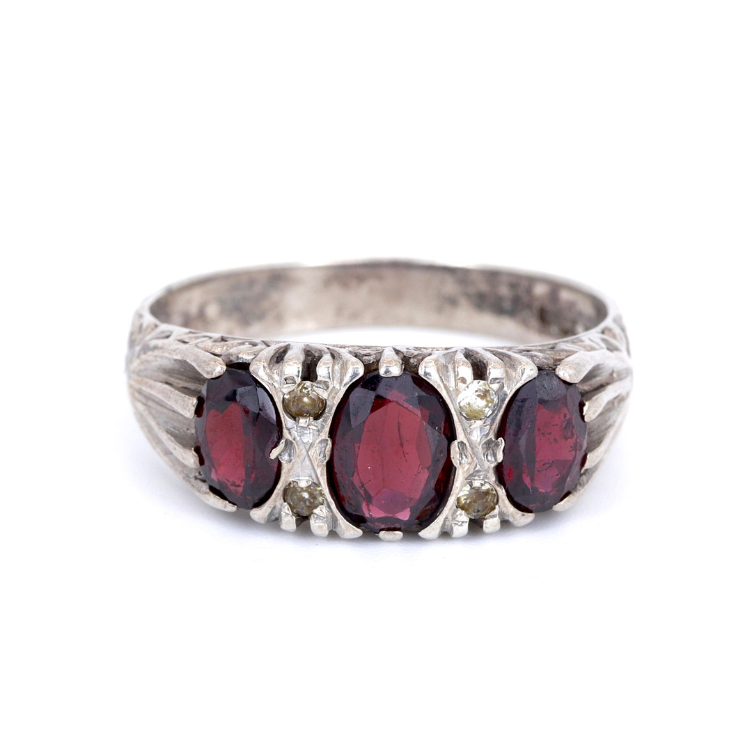 SILVER GARNET SET THREE STONE RING.