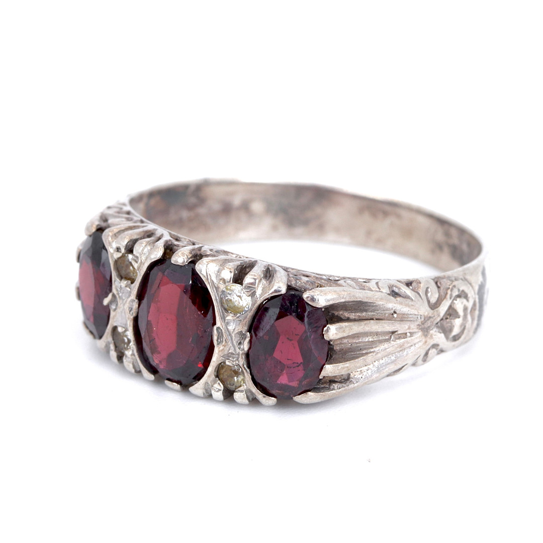 SILVER GARNET SET THREE STONE RING.
