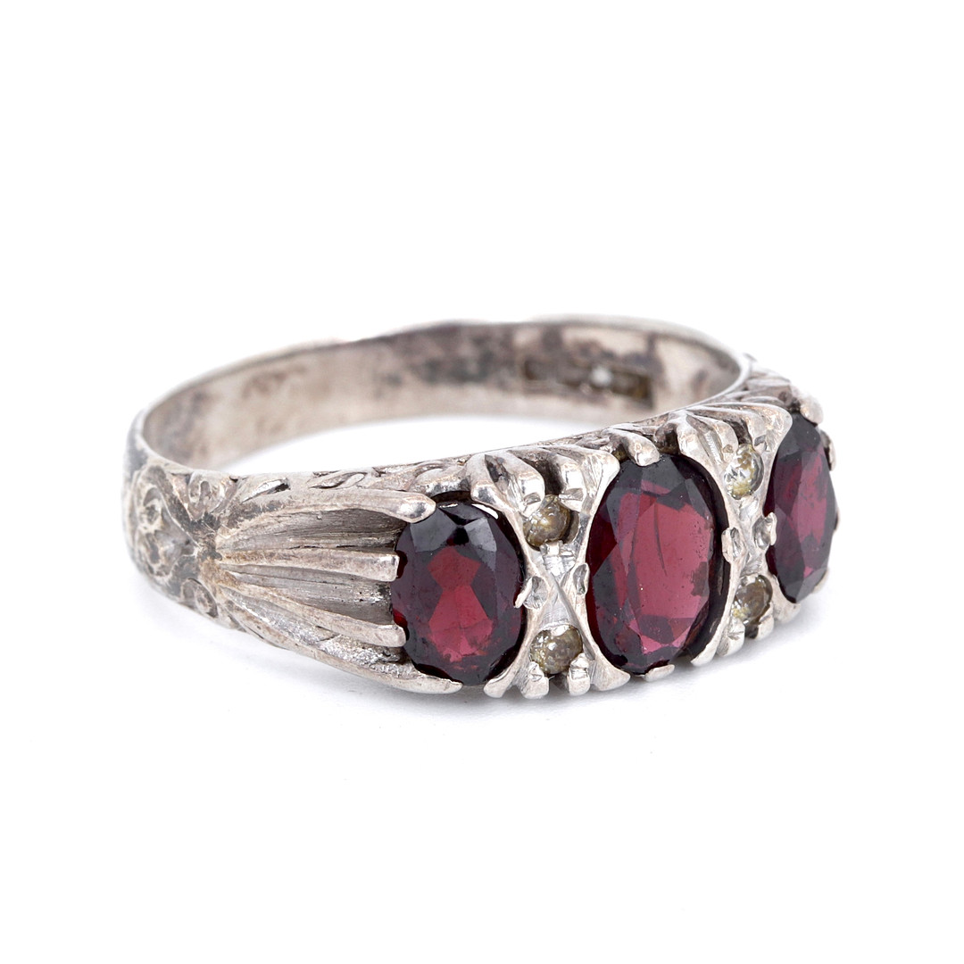 SILVER GARNET SET THREE STONE RING.
