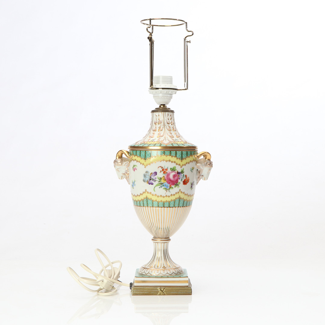 BORDSLAMPA. Porslin med polykrom samt förgylld dekor och mässingsmontering. I form av urna. 1900-talets första hälft.