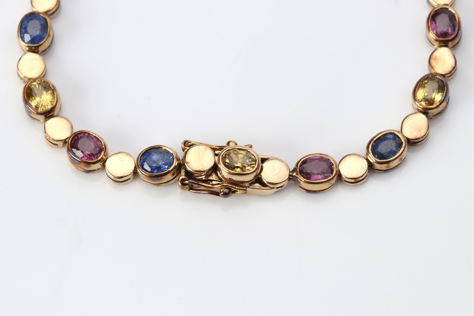 ARMBAND. 14k guld med rödrosa rubiner samt gula och blå safirer, totalvikt ca 8,9 gram.