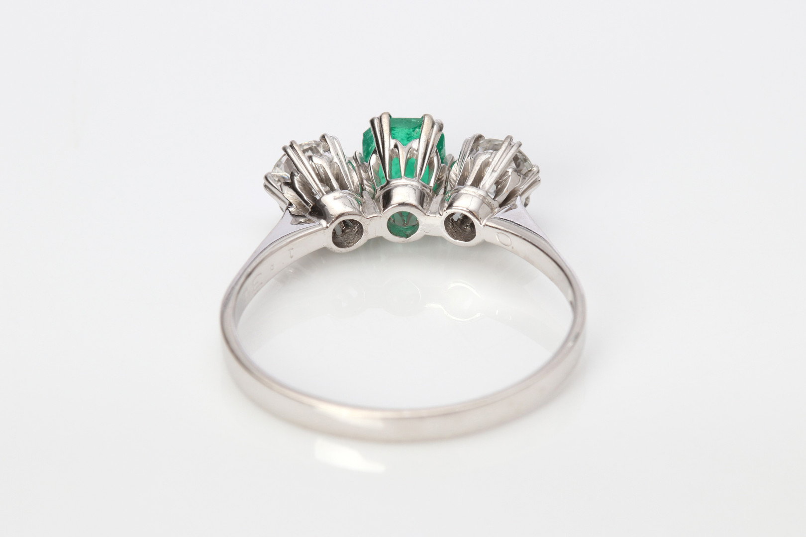 TRILLINGRING. 18k vitguld med två briljantslipade diamanter och en fasetterad smaragd, totalvikt ca 3,2 gram.