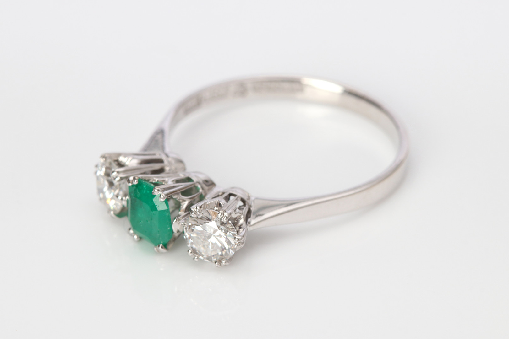 TRILLINGRING. 18k vitguld med två briljantslipade diamanter och en fasetterad smaragd, totalvikt ca 3,2 gram.