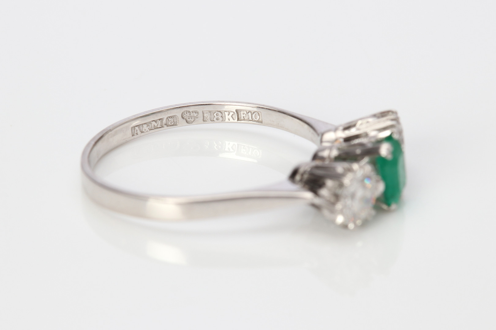TRILLINGRING. 18k vitguld med två briljantslipade diamanter och en fasetterad smaragd, totalvikt ca 3,2 gram.