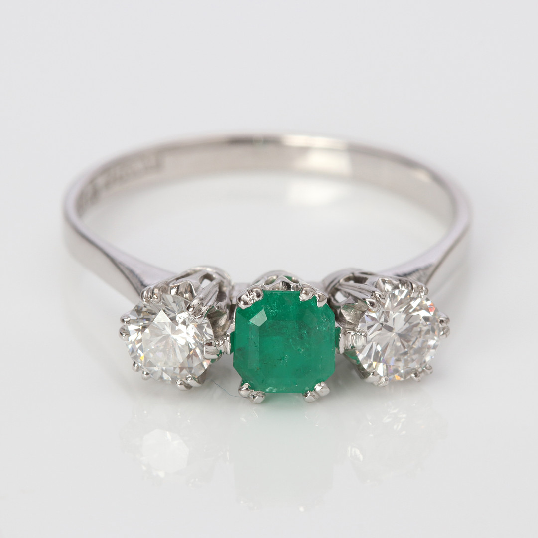 TRILLINGRING. 18k vitguld med två briljantslipade diamanter och en fasetterad smaragd, totalvikt ca 3,2 gram.