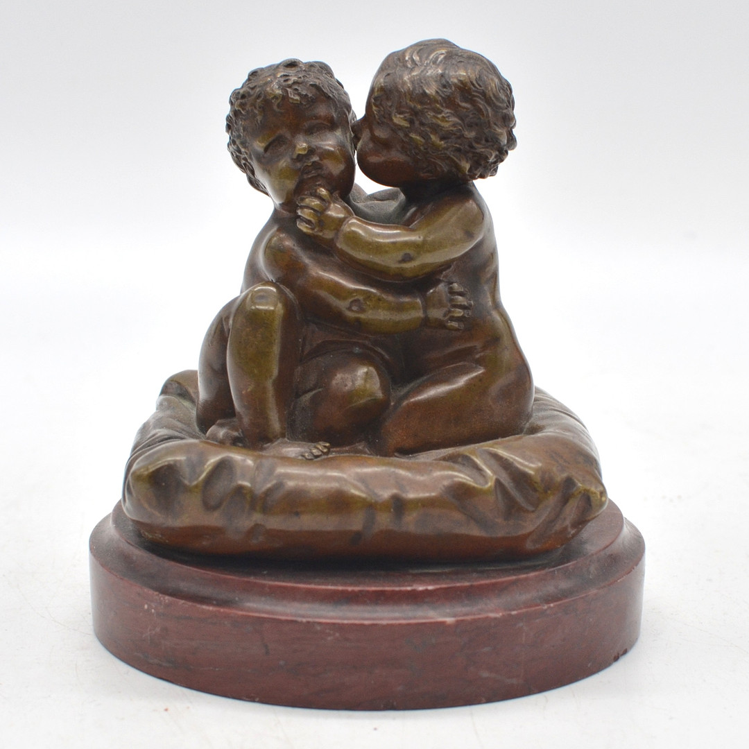LOUIS KLEY (1833-1911). ZWEI UMARMENDE KINDER AUF EINEM KISSEN, SKULPTUR AUS BRONZE MIT STEINSOCKEL IN ROT, UM 1900, FRANKREICH, MIT SIGNIERUNG.