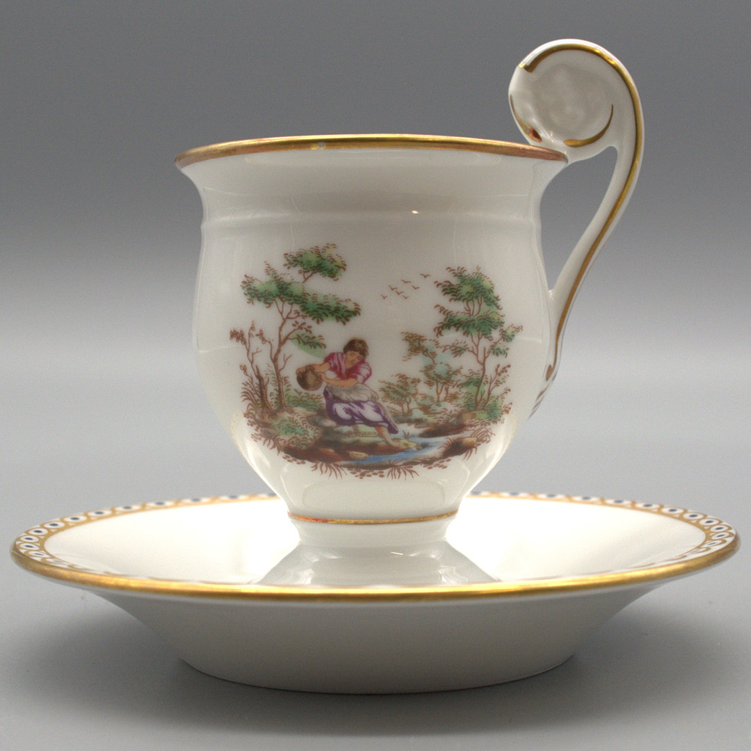 RICHARD GINORI. SET AUS TASSE UND UNTERTASSE, HANDBEMALT MIT GOLDRAND, VERZIERT MIT LÄNDLICHEN GENRESEZENEN.