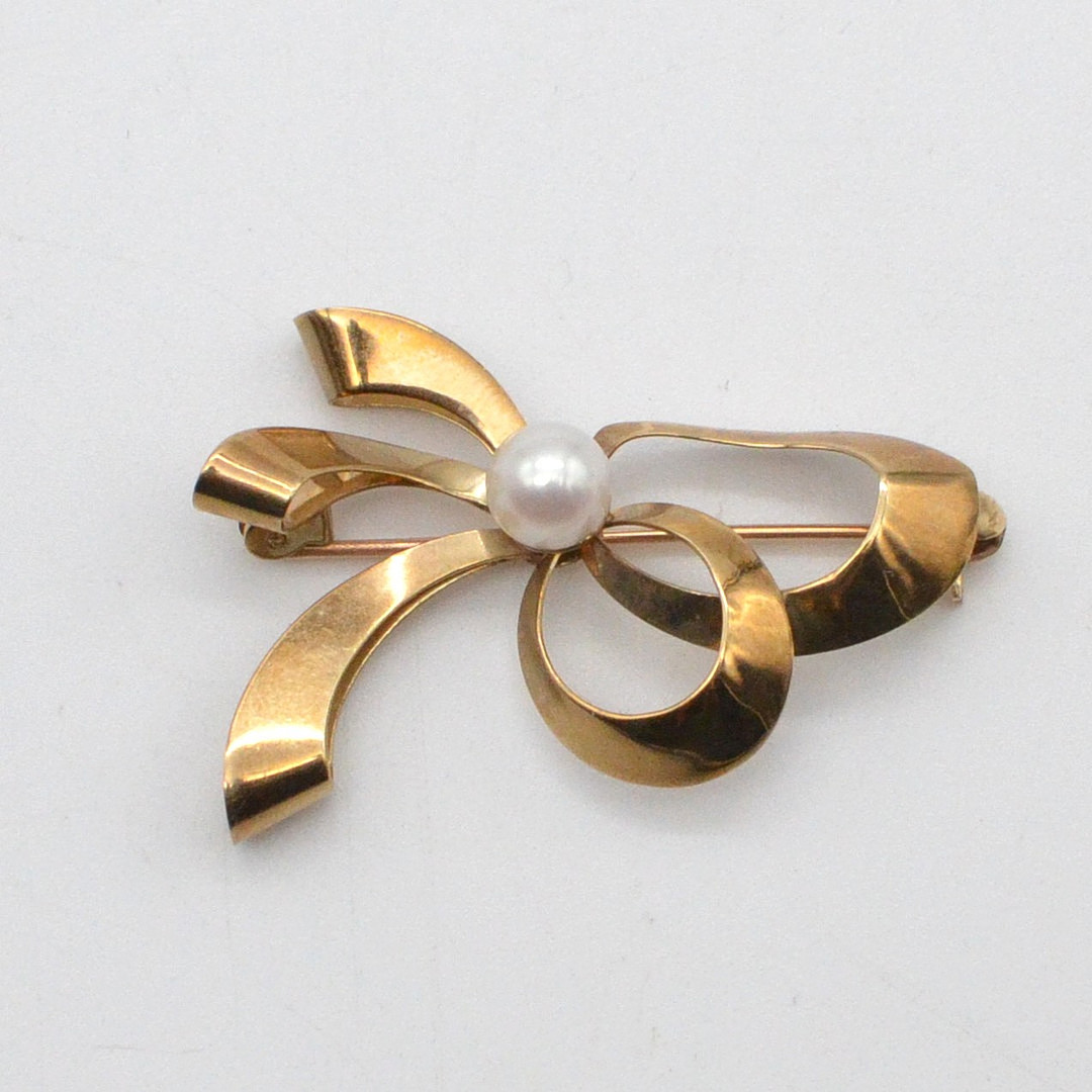 HERMANN SIERSBØL. DESIGNER BROSCHE, SCHLAUFE MIT PERLE, 8 KARAT GELBGOLD (GEPRÜFT), DÄNEMARK, MITTE 20. JAHRHUNDERT.