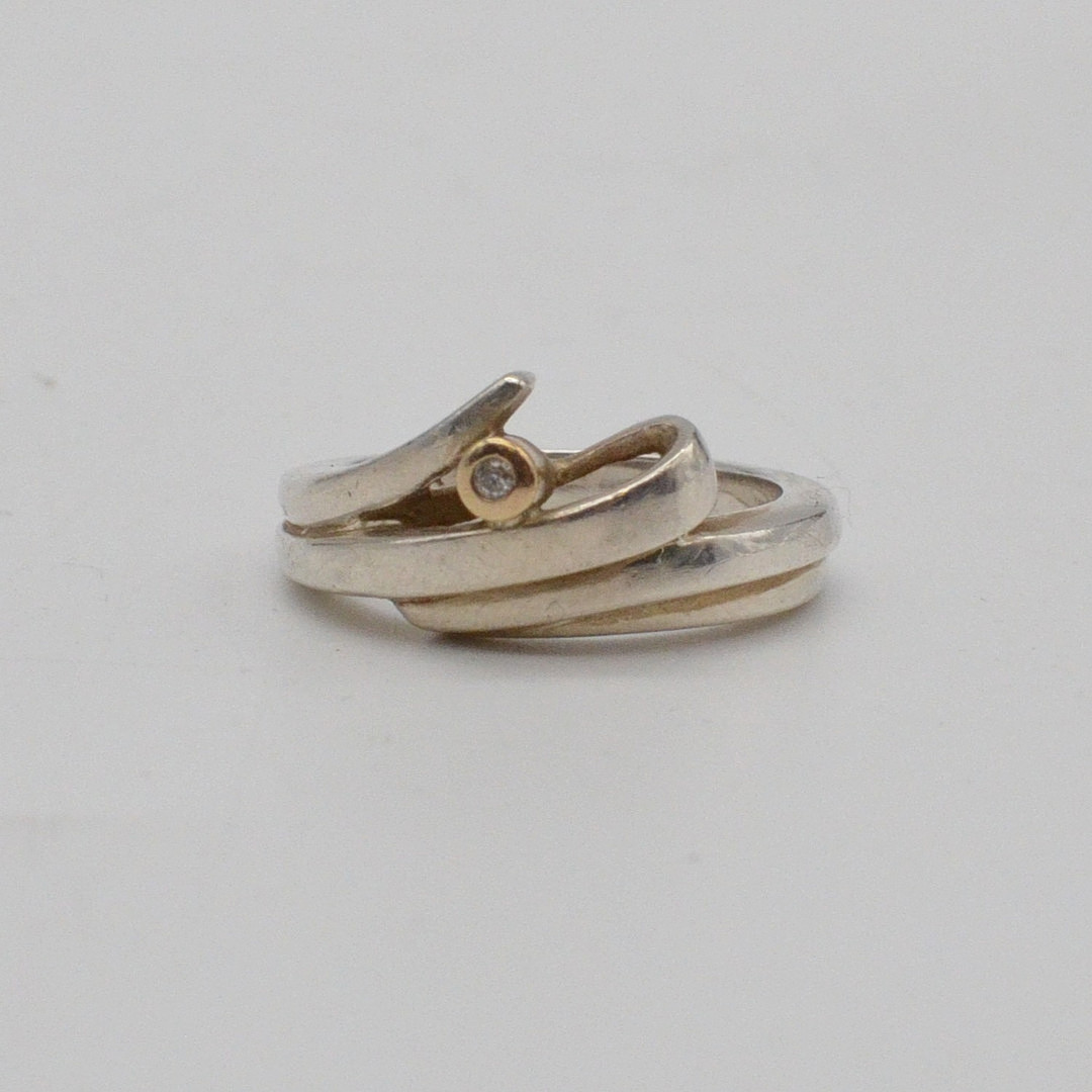 JENS AAGAARD. DESIGNERRING MIT GESCHWUNGENER FORM, STERLINGSILBER MIT VERGOLDETEM DETAIL UND EINEM BRILLANT, DÄNEMARK, UM 1950.