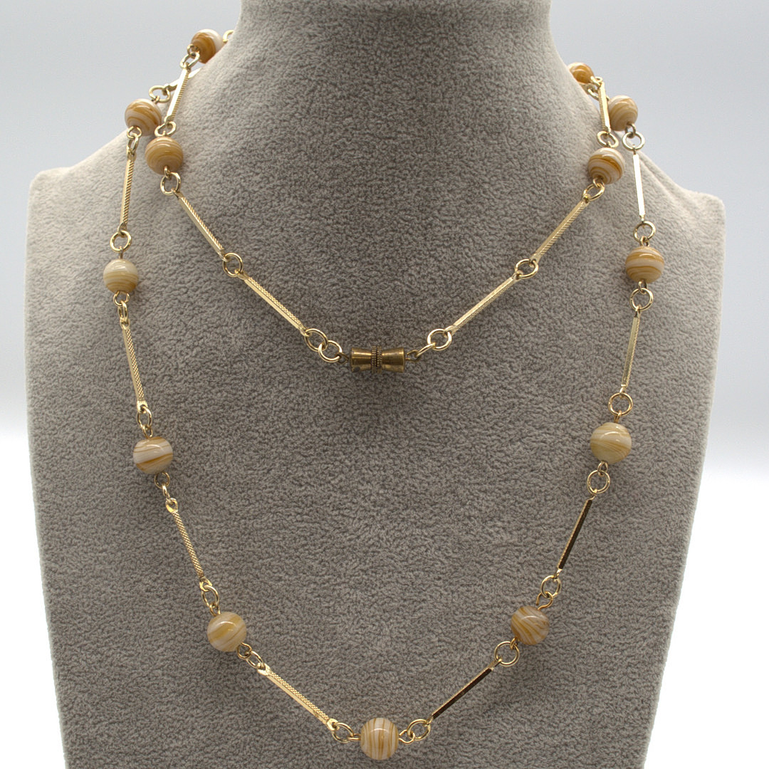 MURANO GLAS COLLIER,MIT CREMEFARBENEN, BERNSTEINFARBIGEN GLAS PERLEN UND VERGOLDETEN METALL VERZIERTEN ZWISCHENELEMENTEN UM CA. 1950 CA. 60 CM.