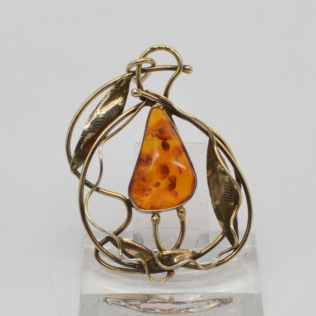 JUGENDSTIL COLLIERANHÄNGER MIT EINEM BERNSTEIN, DURCHBROCHENE FASSUNG AUS VERGOLDETEM STERLINGSILBER, BERNSTEIN MIT BLATTEINSCHLÜSSE, HANDGEMACHT, UNLESERLICH PUNZIERT, FRÜHES 20. JAHRHUNDERT.