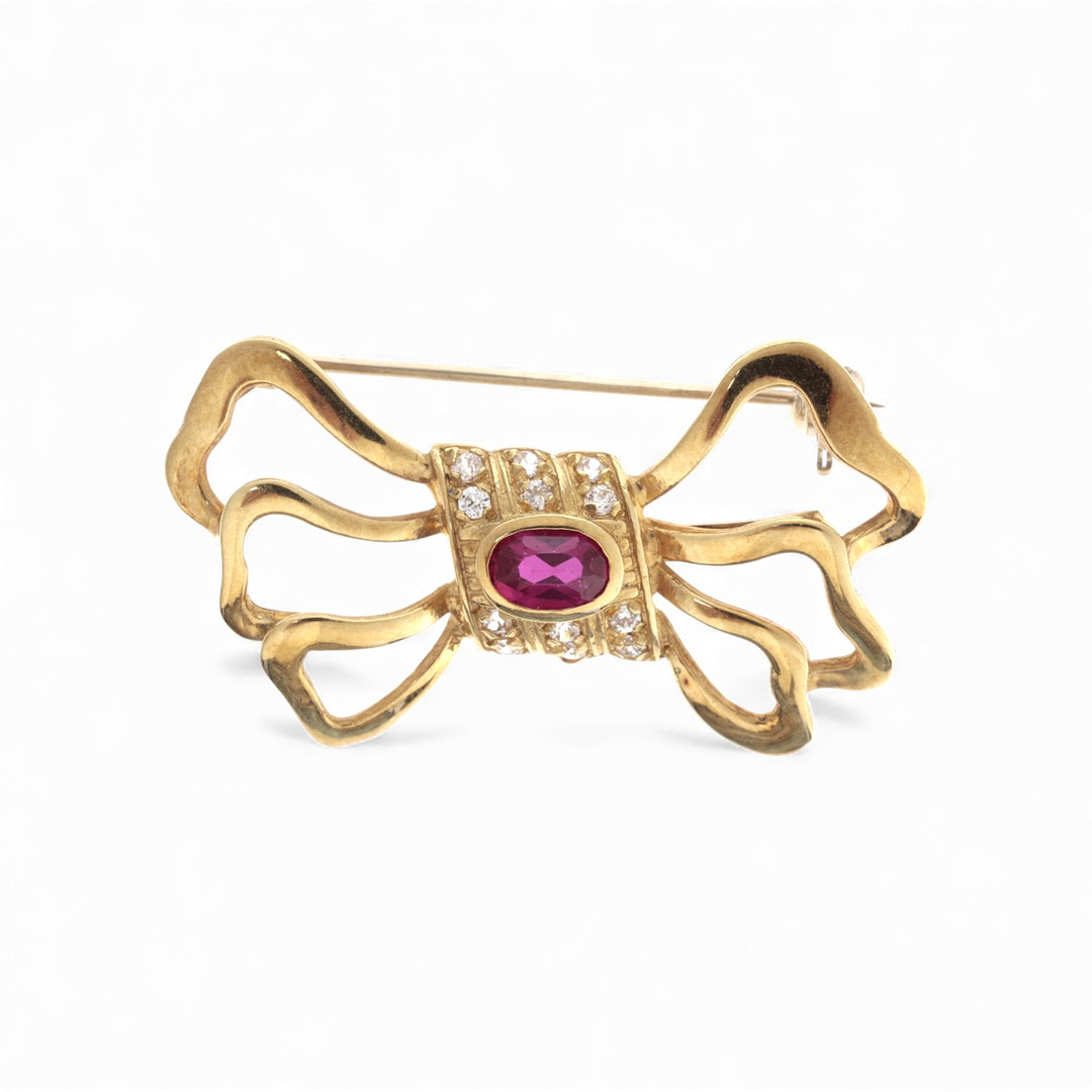 Bow-shaped gold and gemstones brooch.