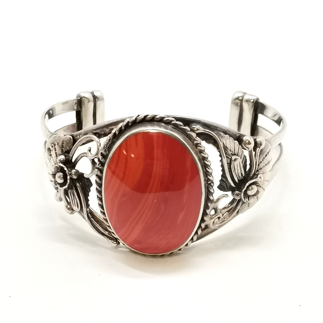 STERLING SILVER BANGLE W/ RED STONE & FLORAL DETAIL.