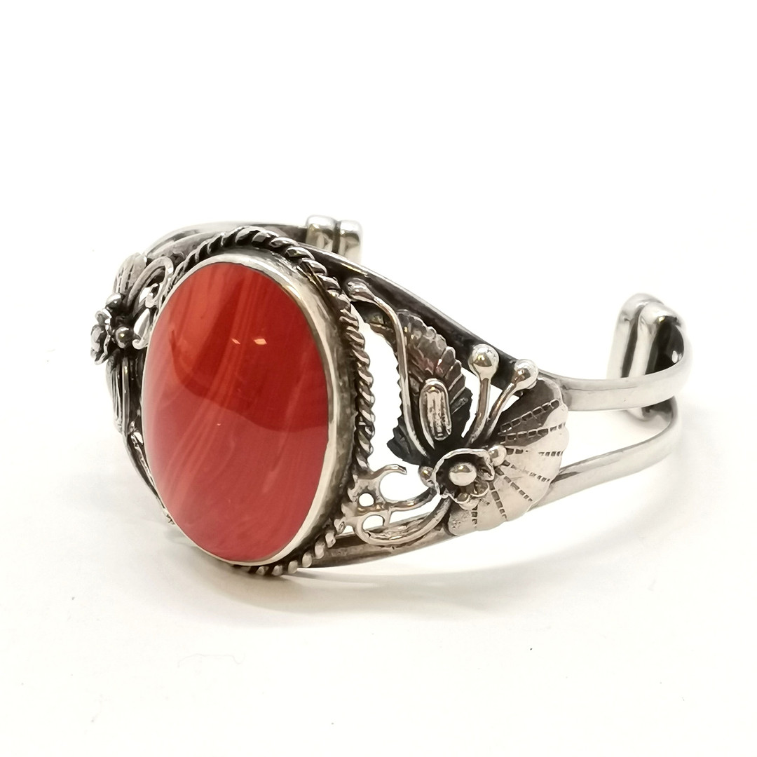 STERLING SILVER BANGLE W/ RED STONE & FLORAL DETAIL.