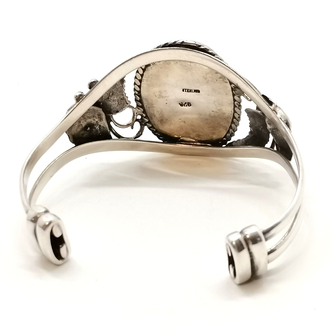 STERLING SILVER BANGLE W/ RED STONE & FLORAL DETAIL.