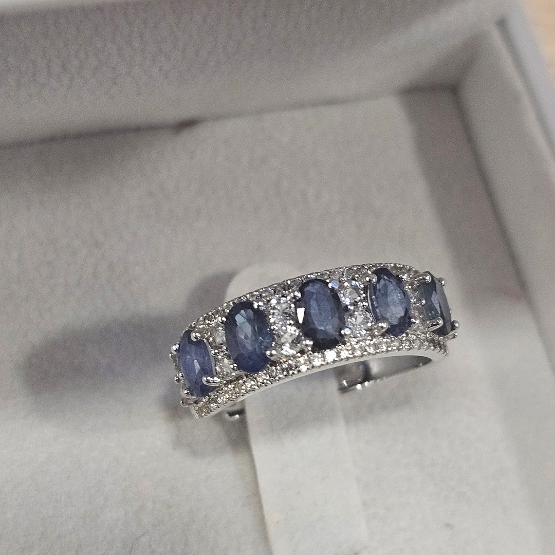 Anillo media alianza en plata con zafiros azules y blancos.
