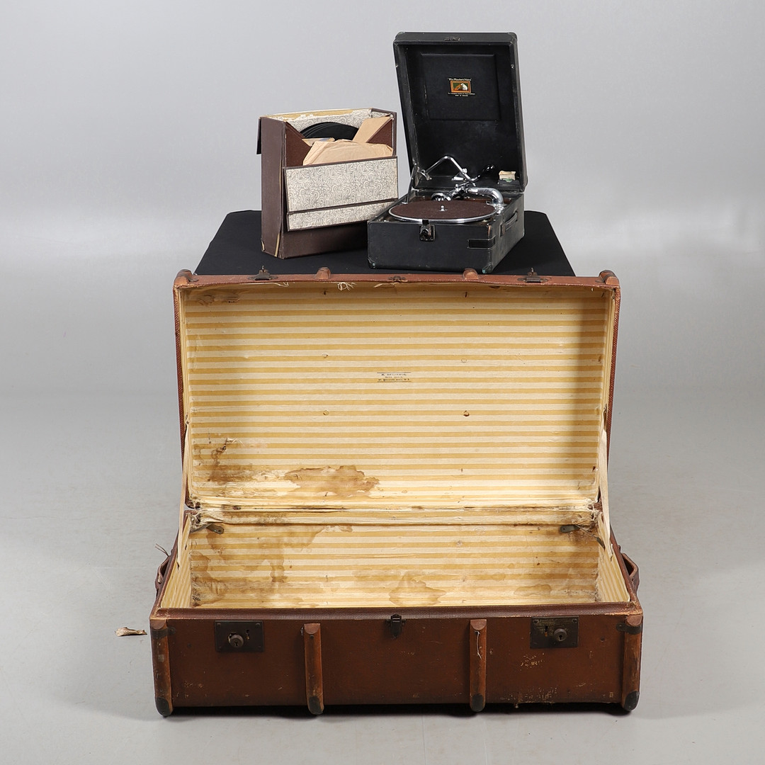 AN EARLY 20TH CENTURY TRAVELLING TRUNK, AND A HMV RECORD PLAYER AND SET OF RECORDS.