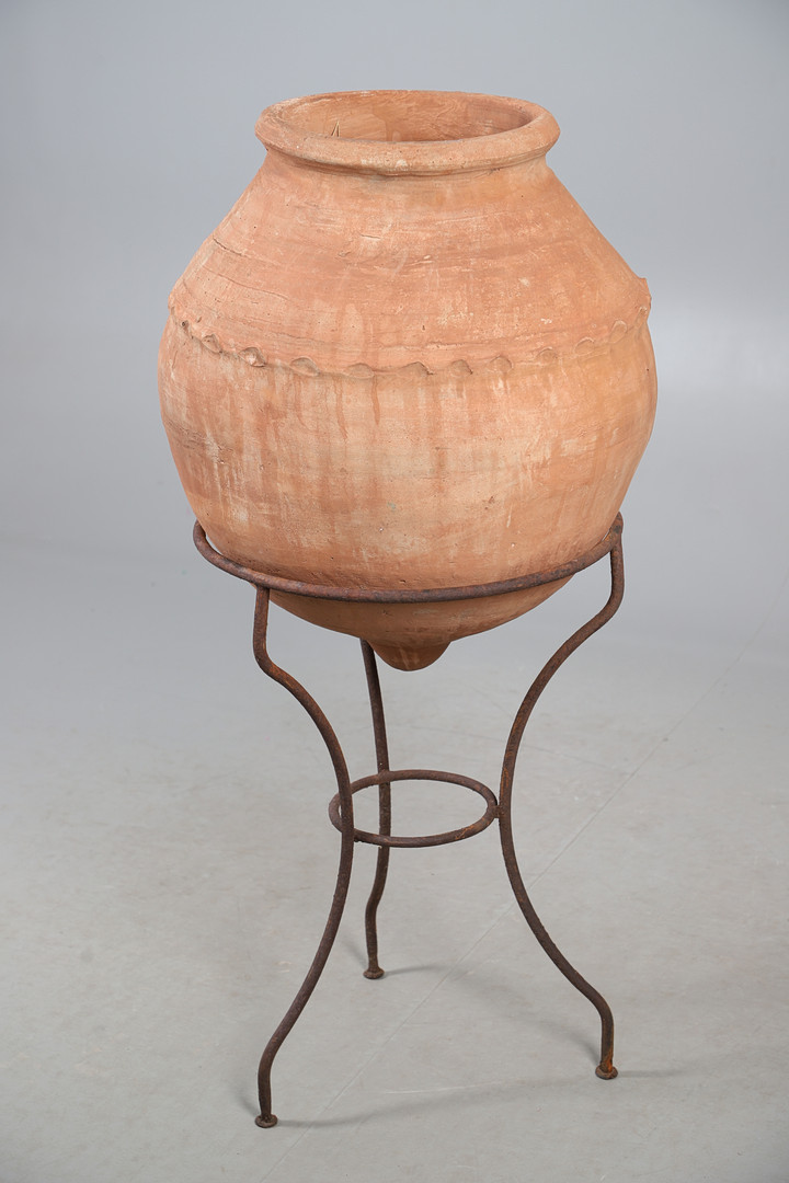 A TERRACOTTA OLIVE (?) JAR ON METAL STAND.