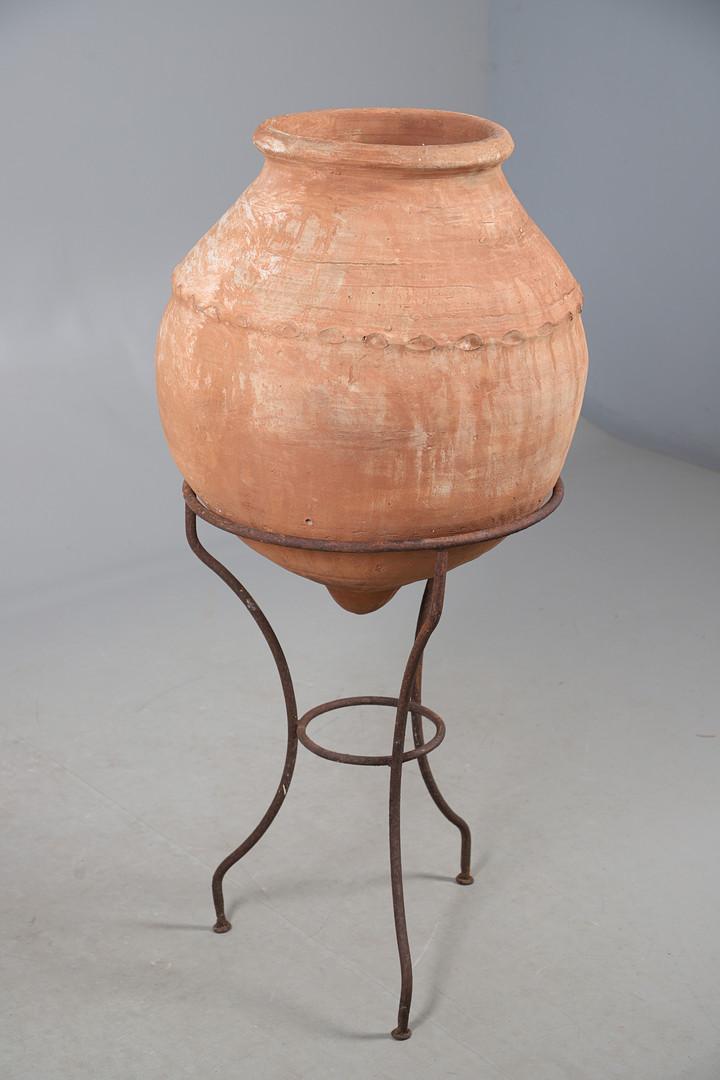 A TERRACOTTA OLIVE (?) JAR ON METAL STAND.