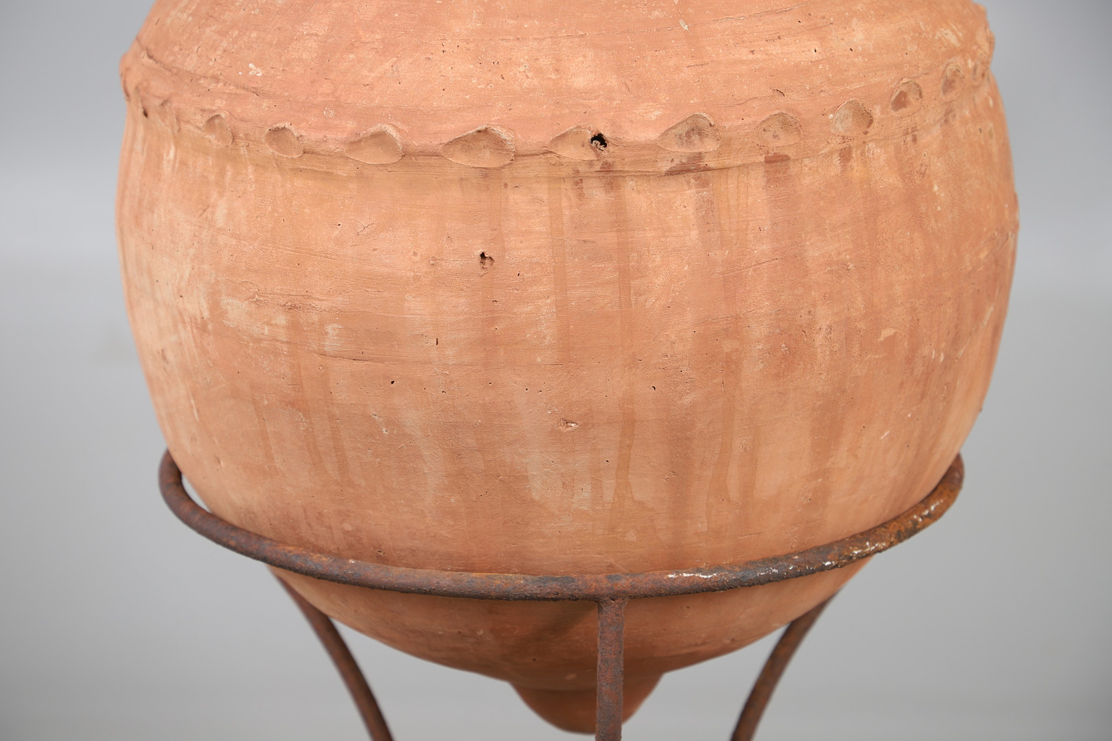 A TERRACOTTA OLIVE (?) JAR ON METAL STAND.