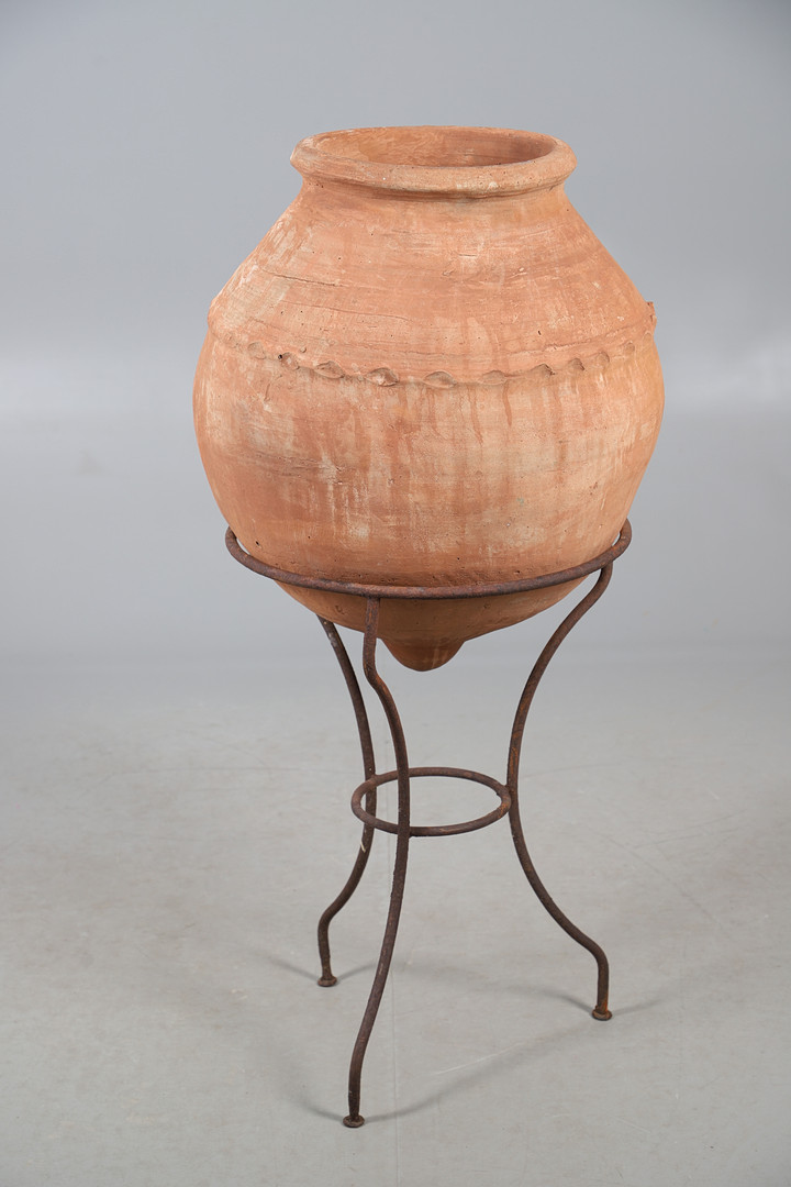 A TERRACOTTA OLIVE (?) JAR ON METAL STAND.