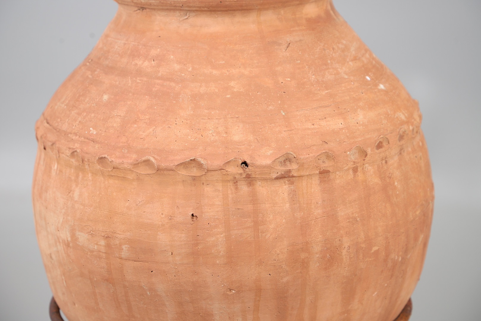 A TERRACOTTA OLIVE (?) JAR ON METAL STAND.
