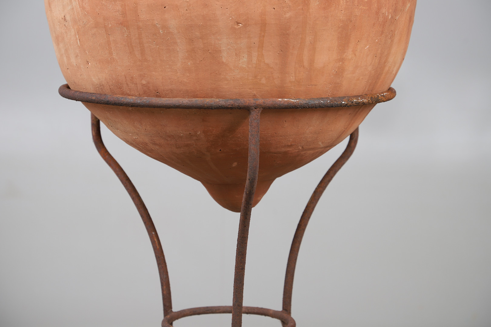 A TERRACOTTA OLIVE (?) JAR ON METAL STAND.