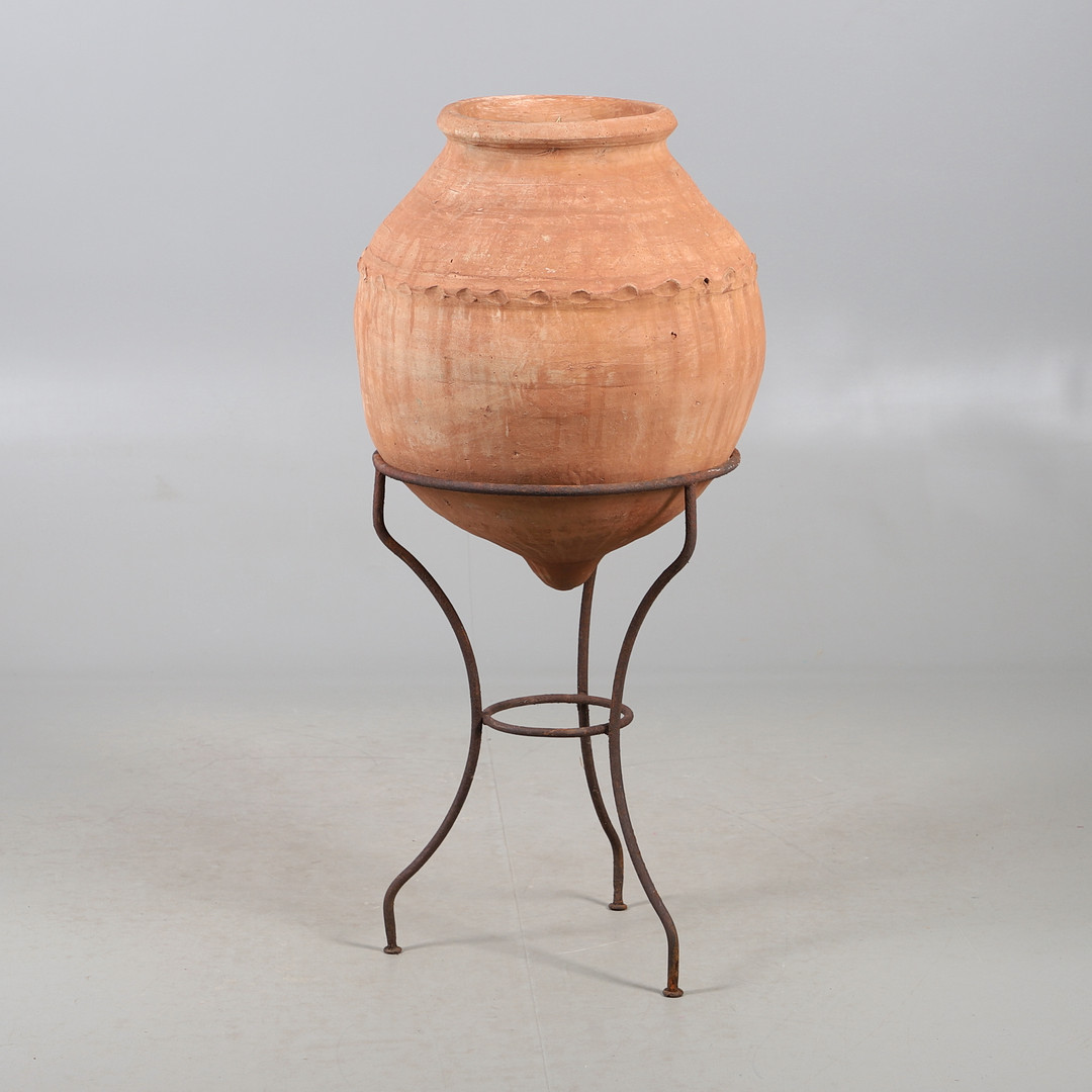 A TERRACOTTA OLIVE (?) JAR ON METAL STAND.