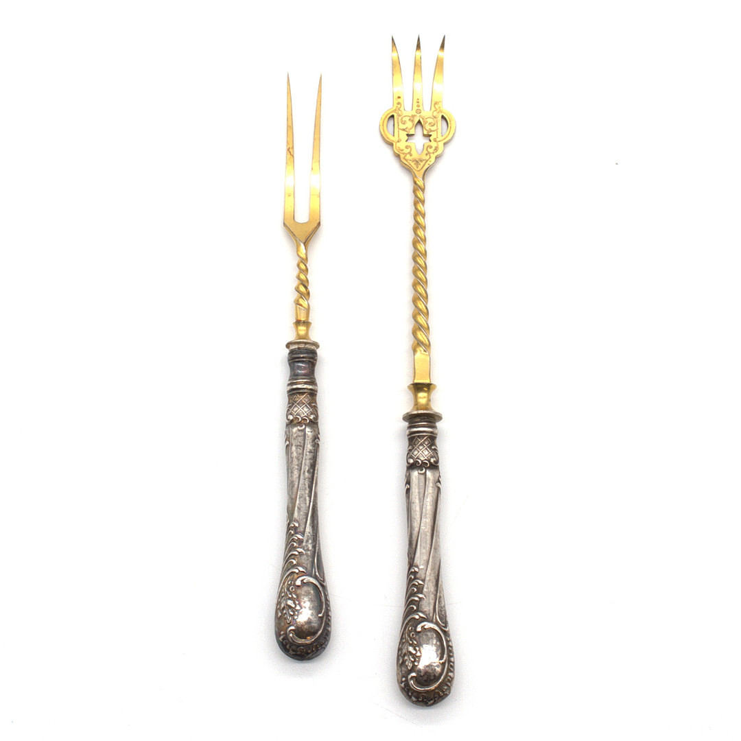 VORLEGEBESTECK, GRIFFE AUS 800ER SILBER, ZINKEN AUS VERGOLDETEN METALL, HALBMOND UND KRONE, HISTORISMUS DEKOR, UM 1890.