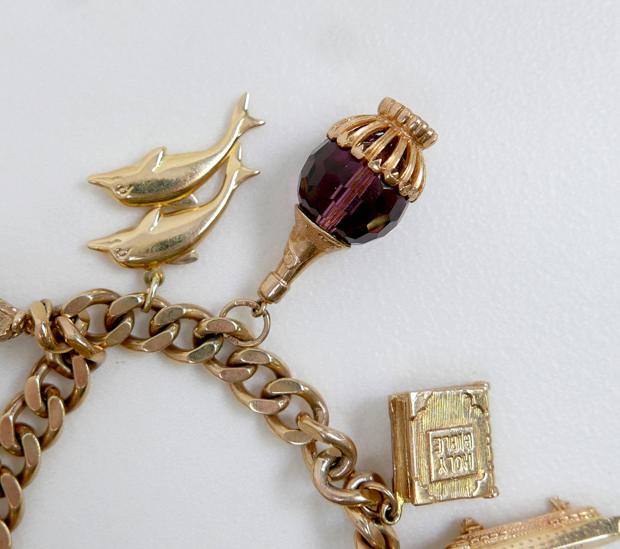 A 9CT GOLD CHARM BRACELET, FLAT CURB, WITH ASSORTED 9CT AND 14CT GOLD CHARMS.