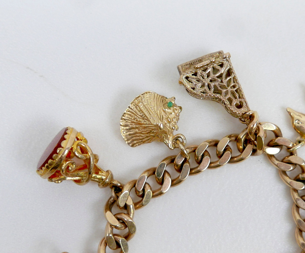 A 9CT GOLD CHARM BRACELET, FLAT CURB, WITH ASSORTED 9CT AND 14CT GOLD CHARMS.