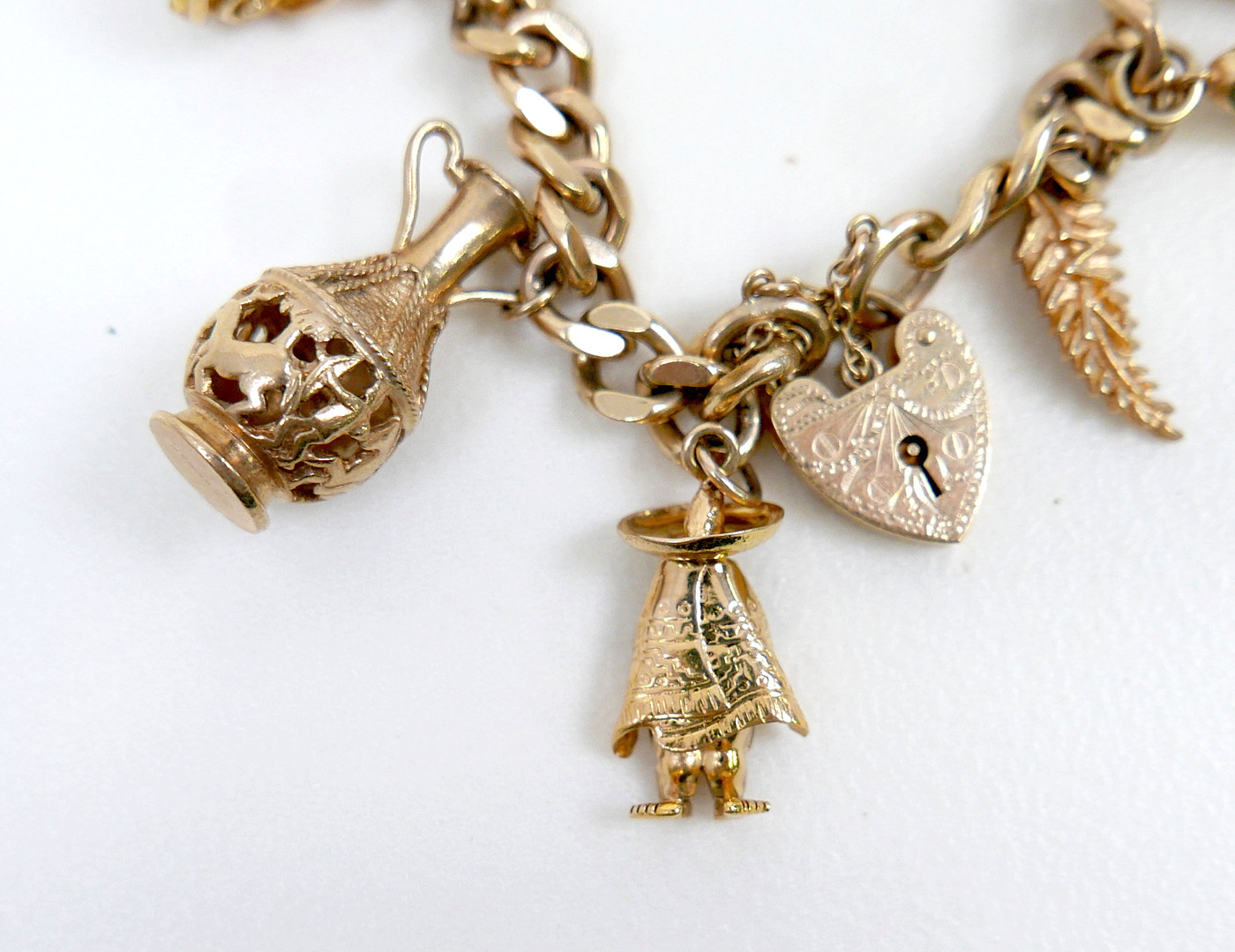 A 9CT GOLD CHARM BRACELET, FLAT CURB, WITH ASSORTED 9CT AND 14CT GOLD CHARMS.