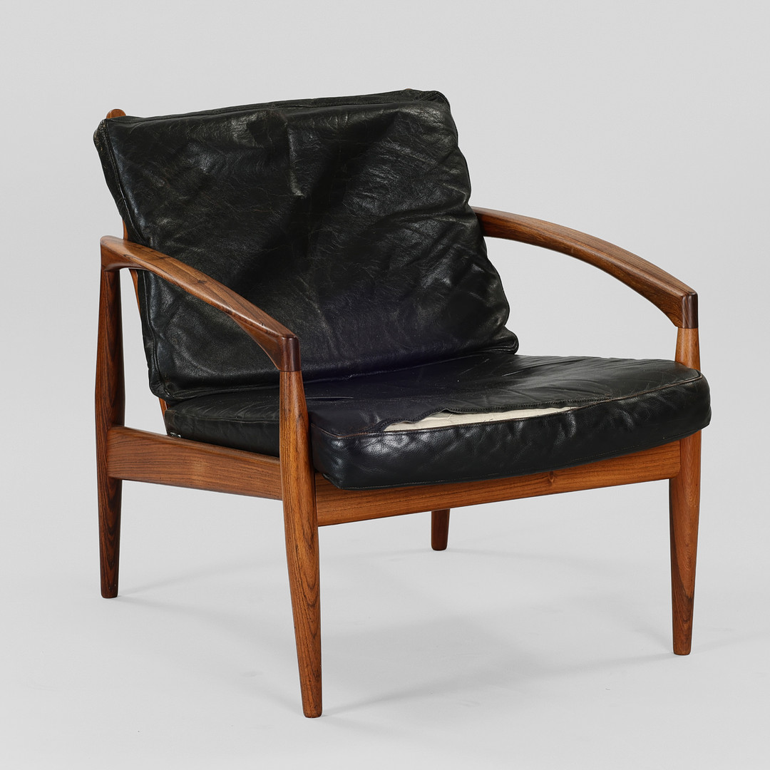 KAI KRISTIANSEN. "Papirkniven”, lænestol med stel af palisander, hynder betrukket med sort læder, model 121, Magnus Olesen, Danmark, formgivet 1955.