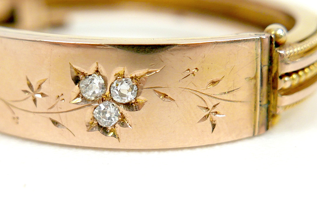A 19TH/EARLY 20TH CENTURY YELLOW METAL AND DIAMOND HINGED BANGLE.